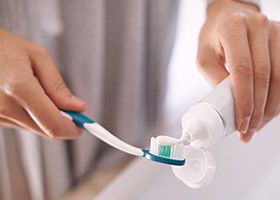 Person putting toothpaste on toothbrush